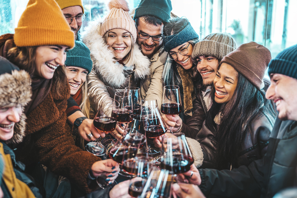 Friends in winter clothes cheers with wine glasses