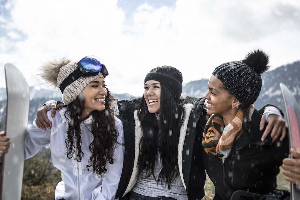 three girls sitting outside with ski gear
